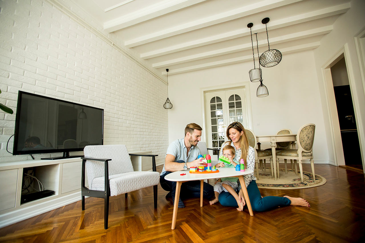Boldog család egy modern nappaliban hagyományos étkezőgarnitúrával